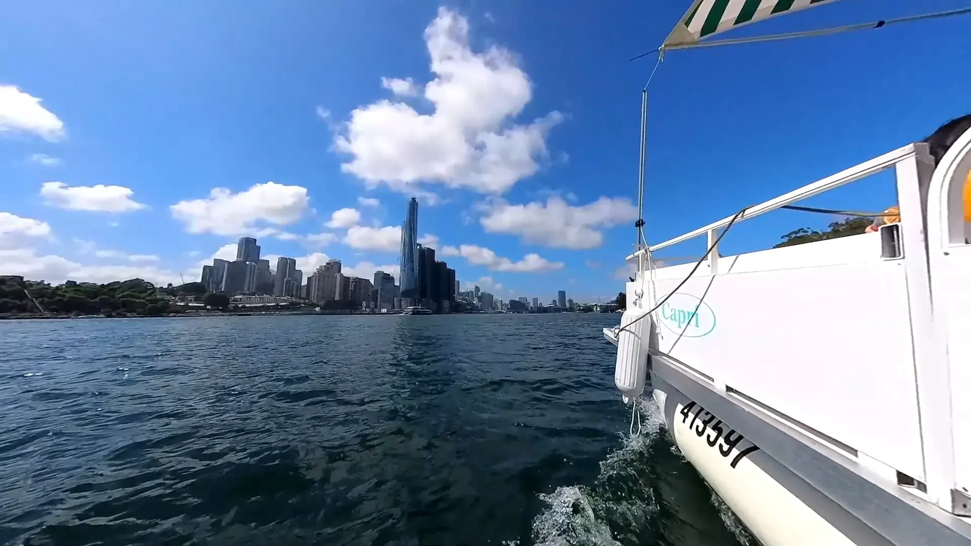 A boat is floating on a body of water with a city skyline in the background
