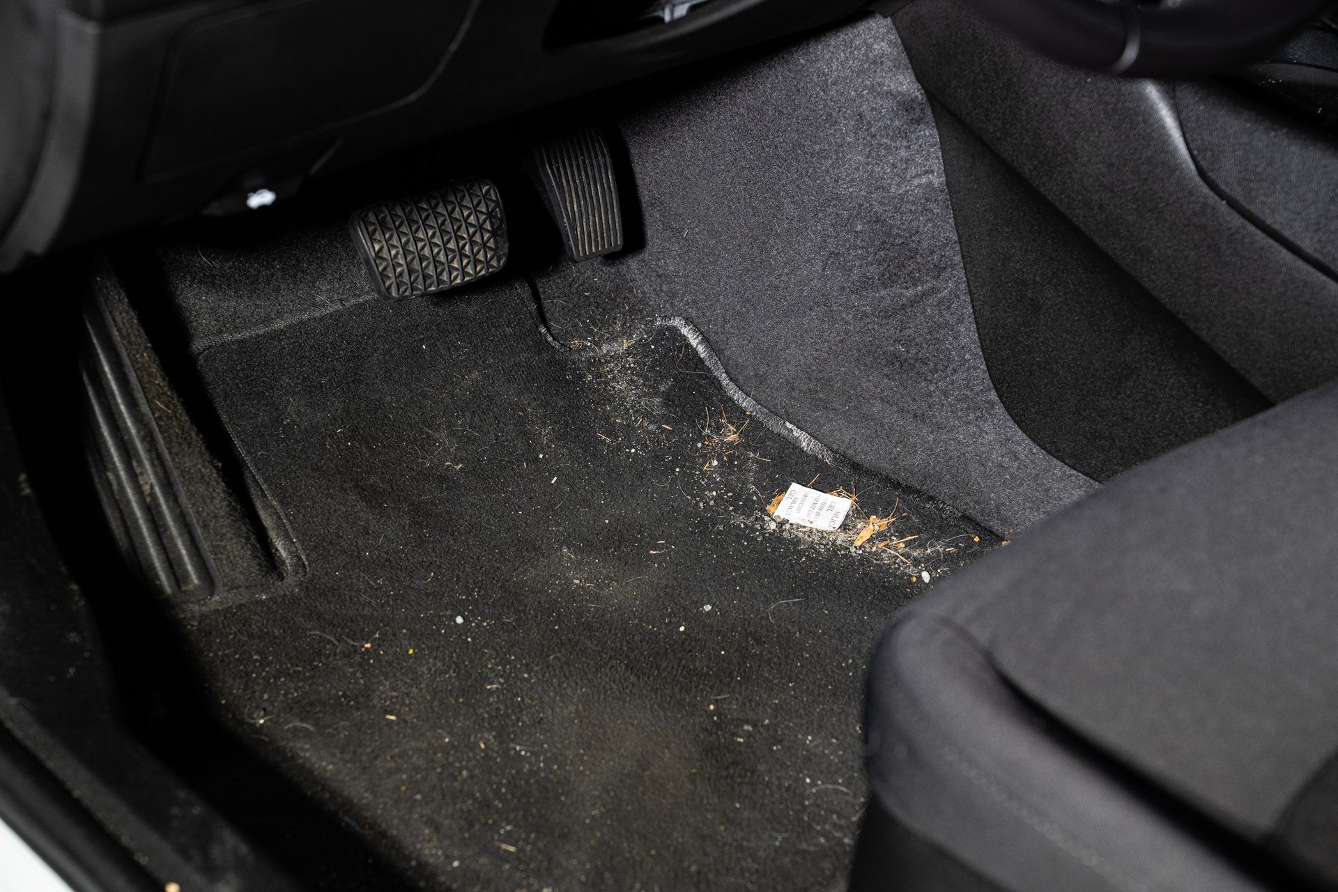 Car floor mats and black carpet with a wet, muddy stain near the driver’s seat