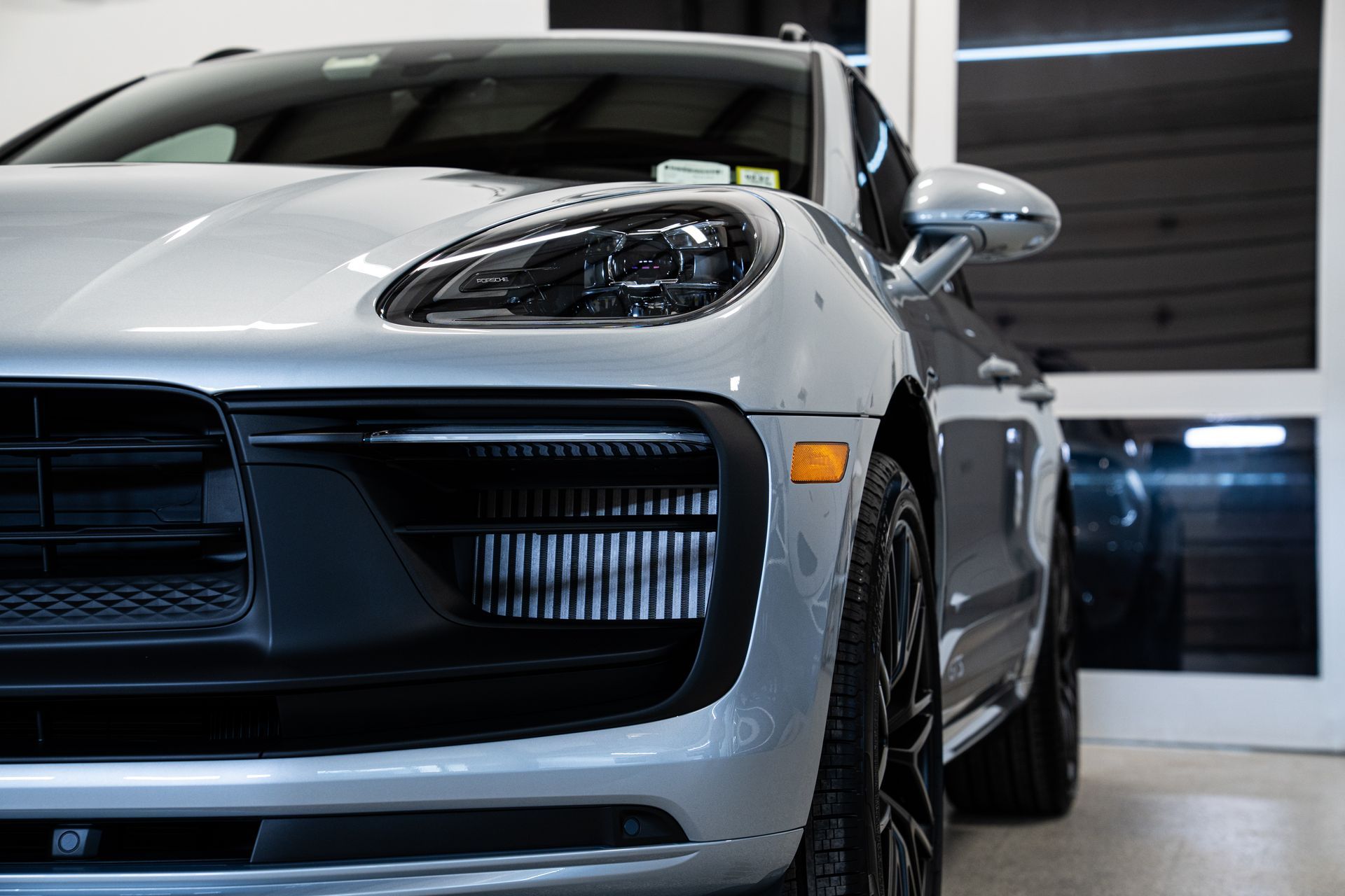 Silver sports car in a showroom, front view with sleek headlights and black grille