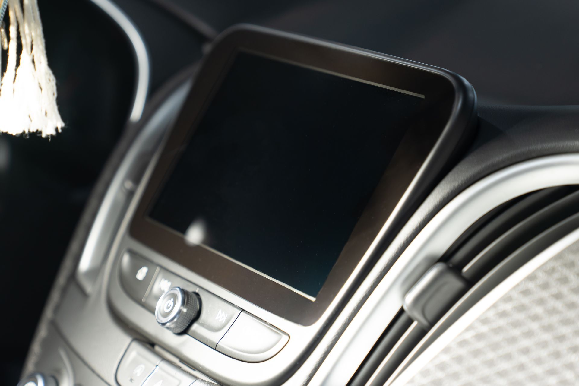 Car dashboard infotainment screen with silver controls and black display, close-up view