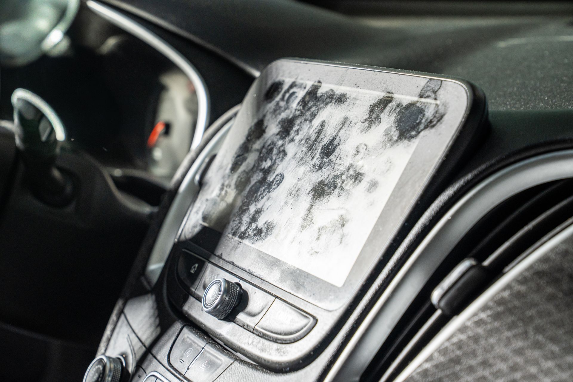 Car center console with a phone mount and a partially frost-covered windshield.