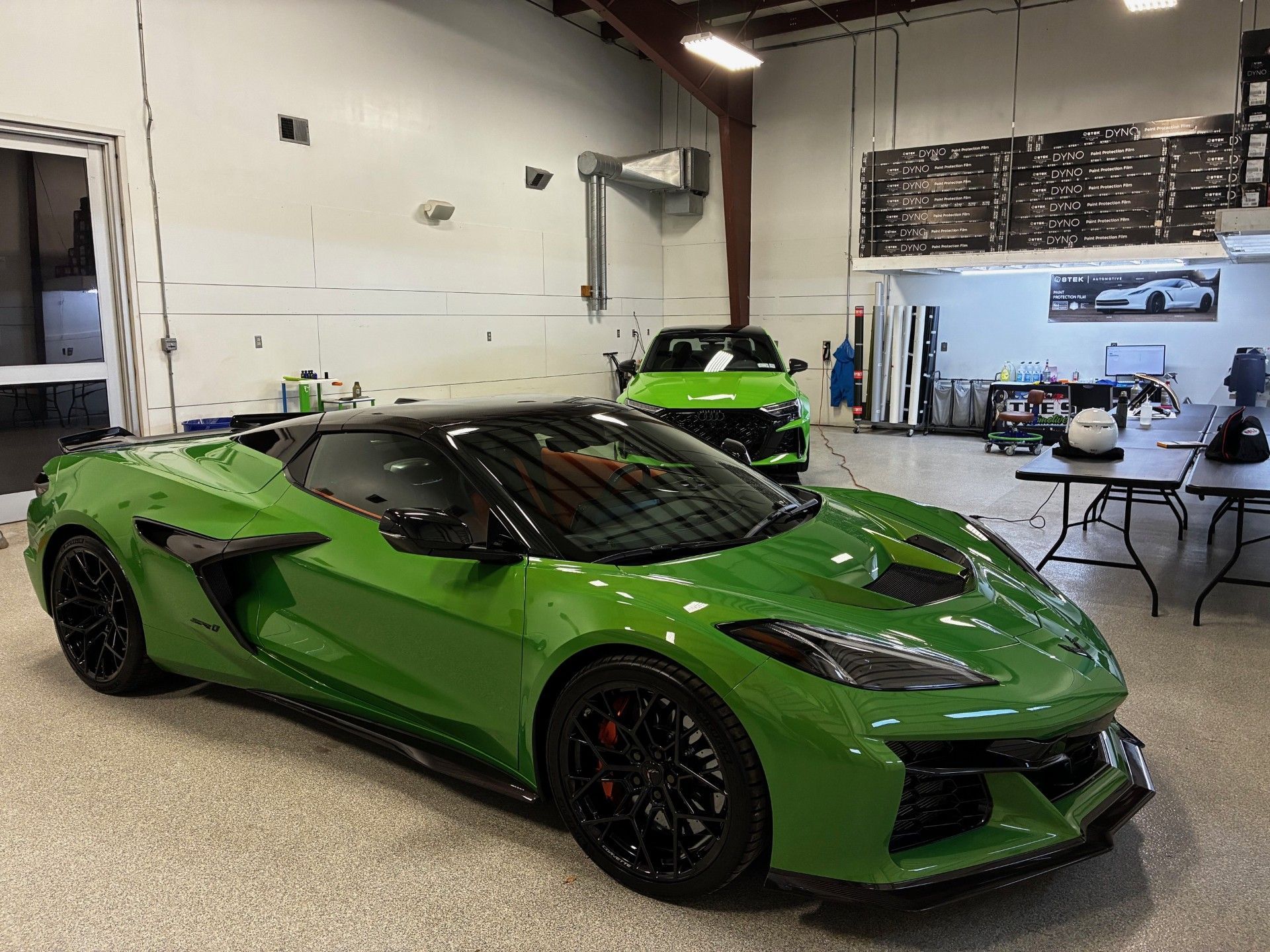 Bright green sports car in a garage with tables and tools in the background