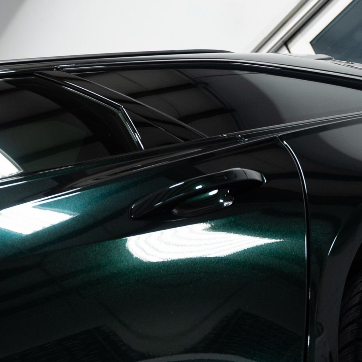 Blue sports car in a garage, shown after detailing, with glossy black wheels and an open hood.