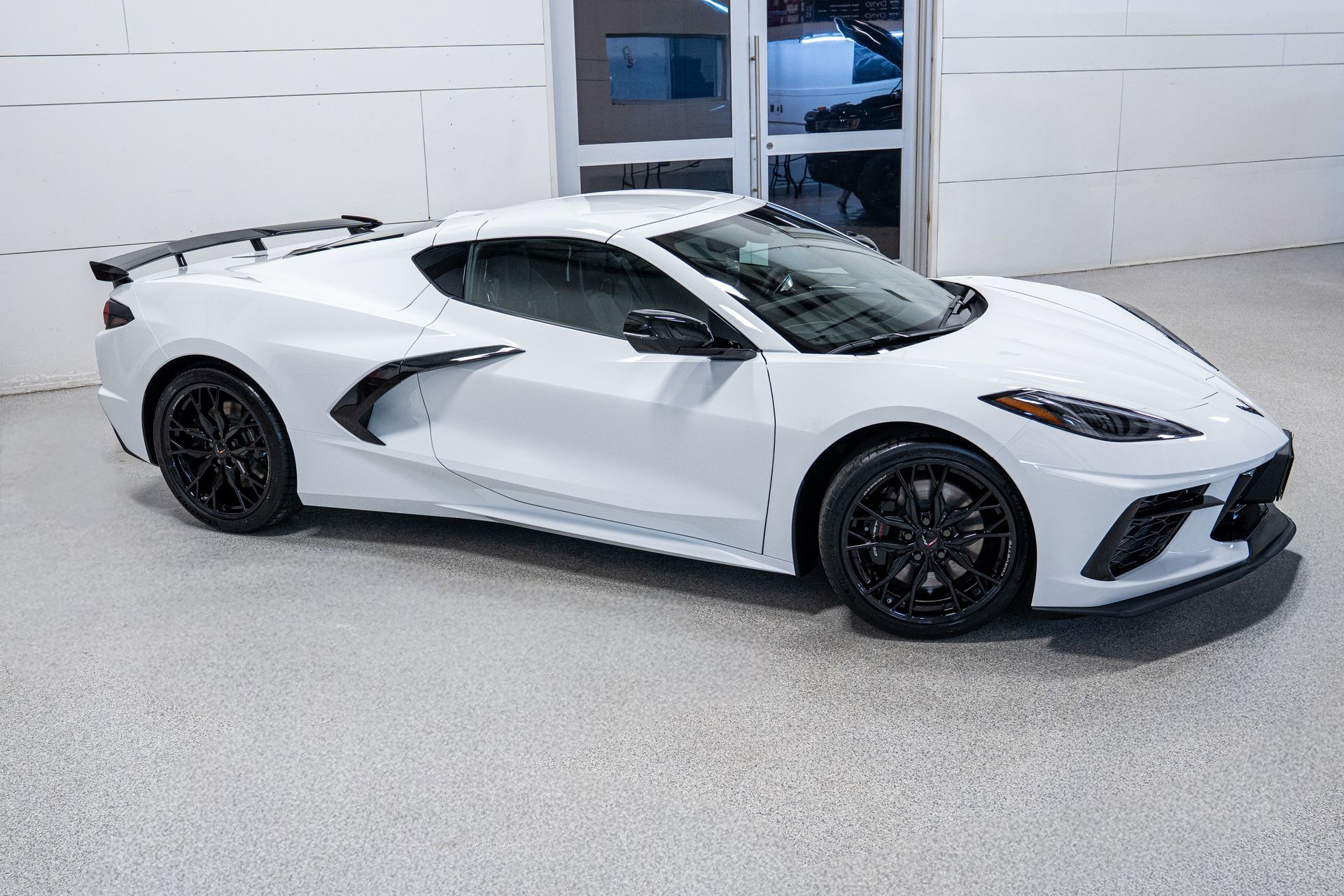 White sports car parked indoors in front of a garage door