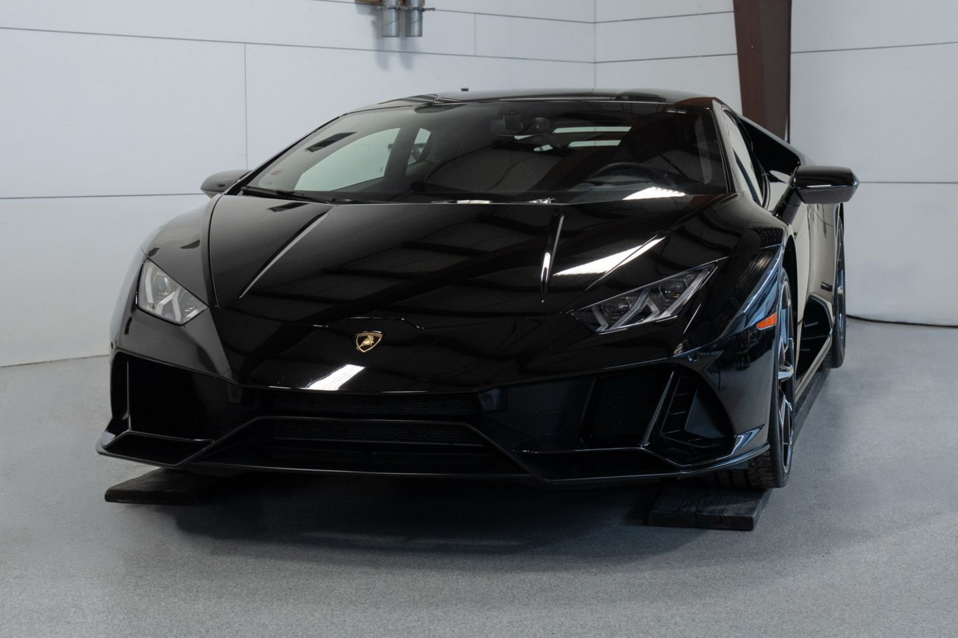 Black Lamborghini sports car parked indoors in a showroom-like garage.