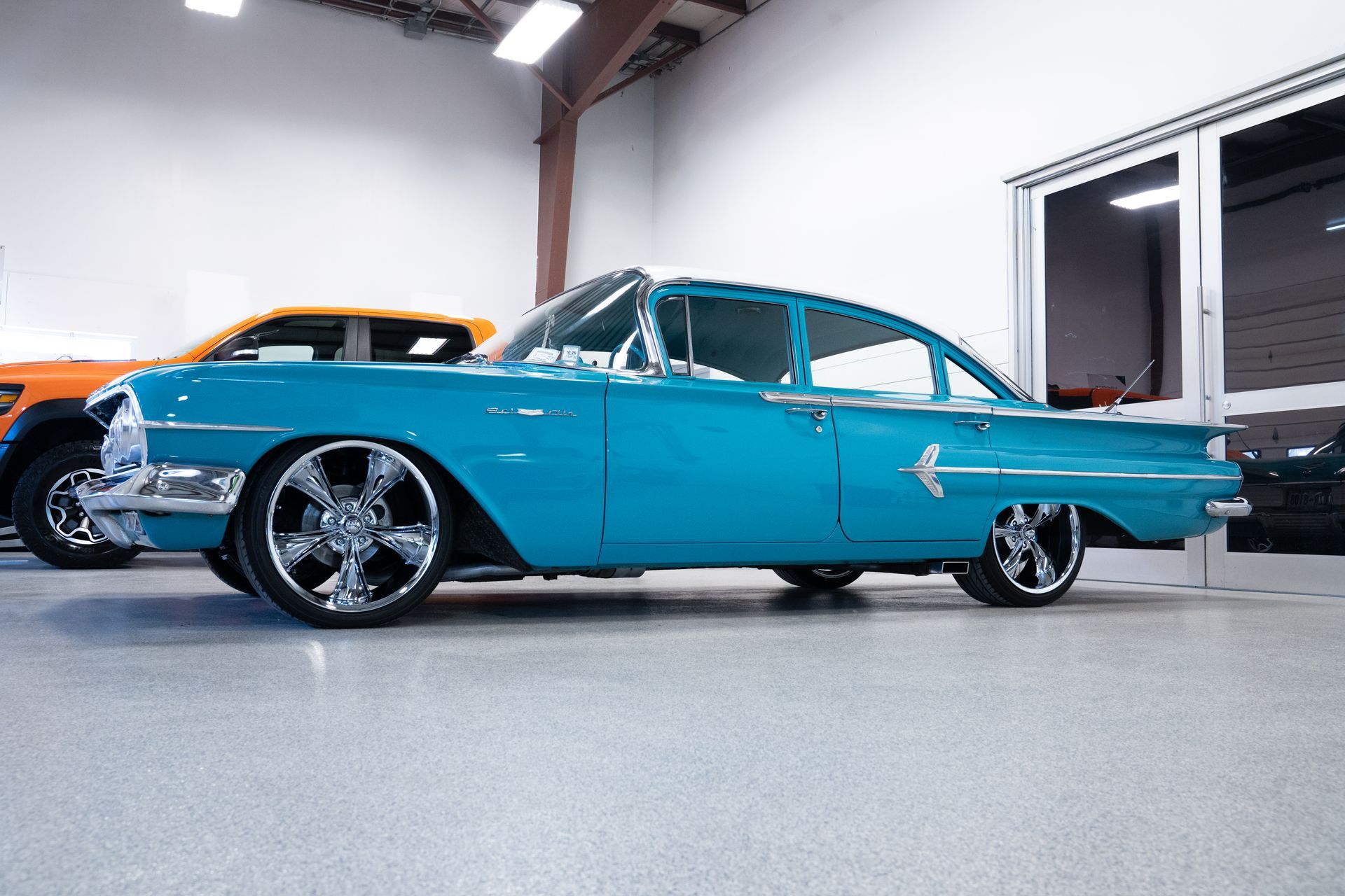 Turquoise classic car with chrome details parked indoors in a garage