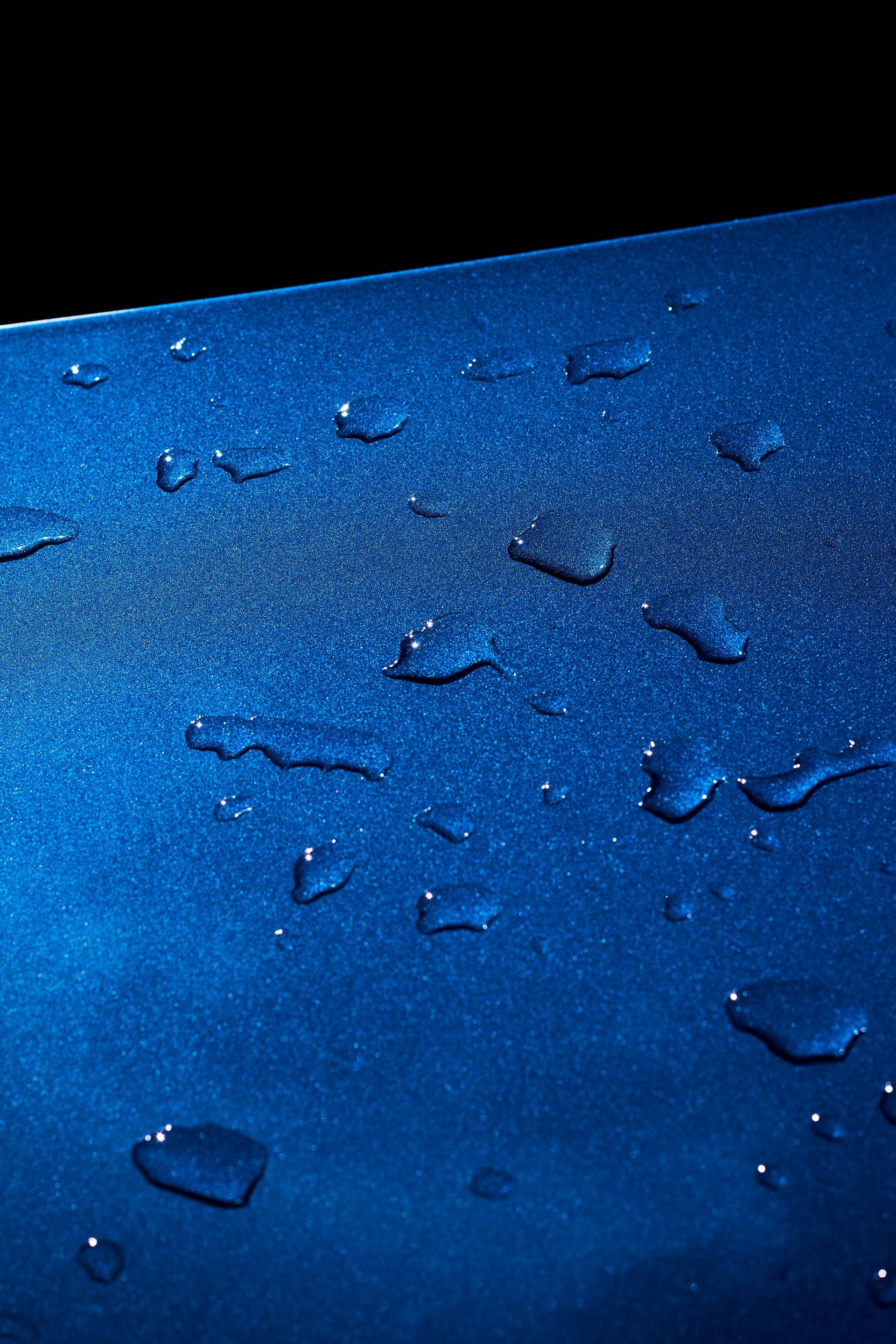 Blue water droplets on a dark blue surface, with a black background at the top.
