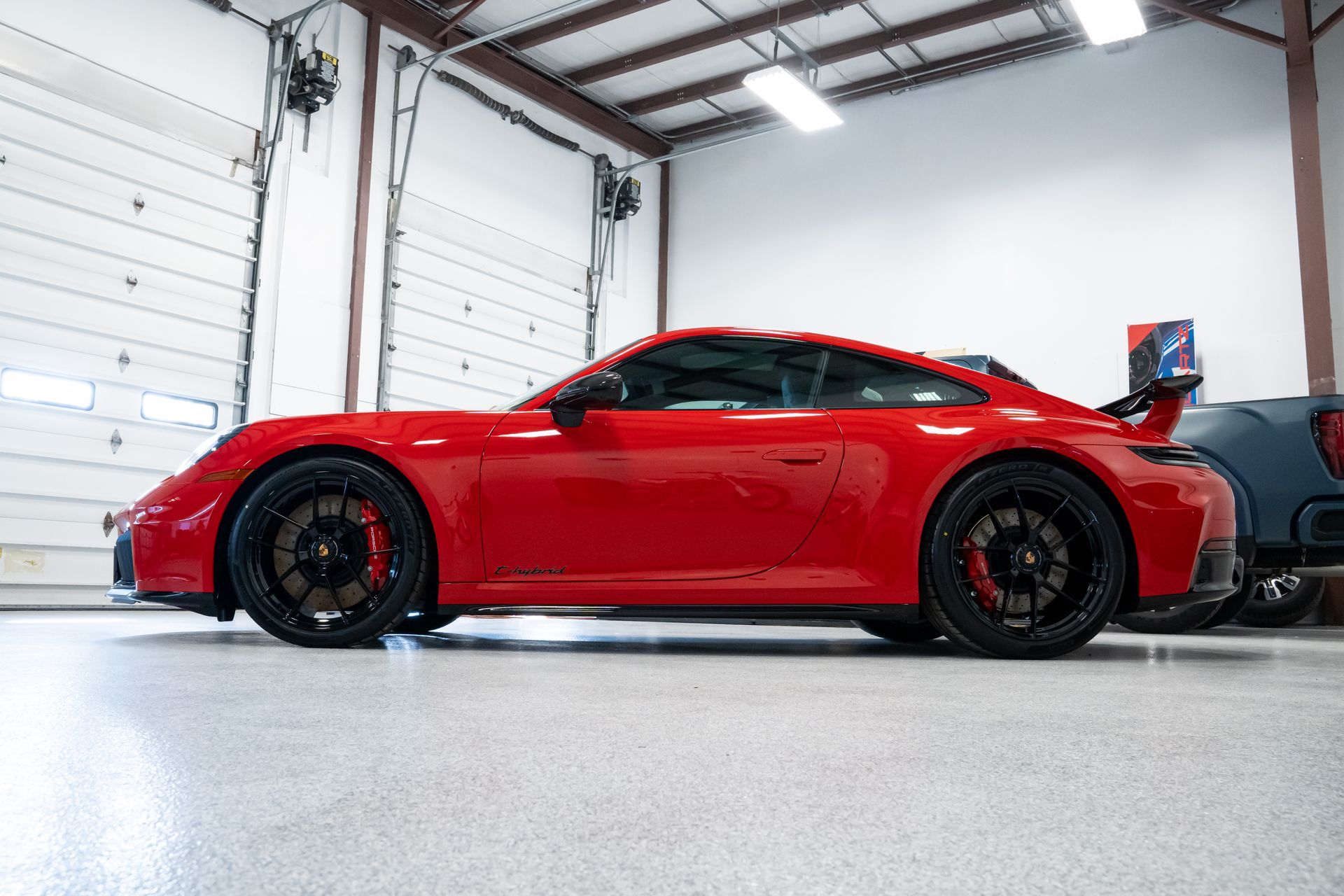 Red sports car parked inside a bright garage