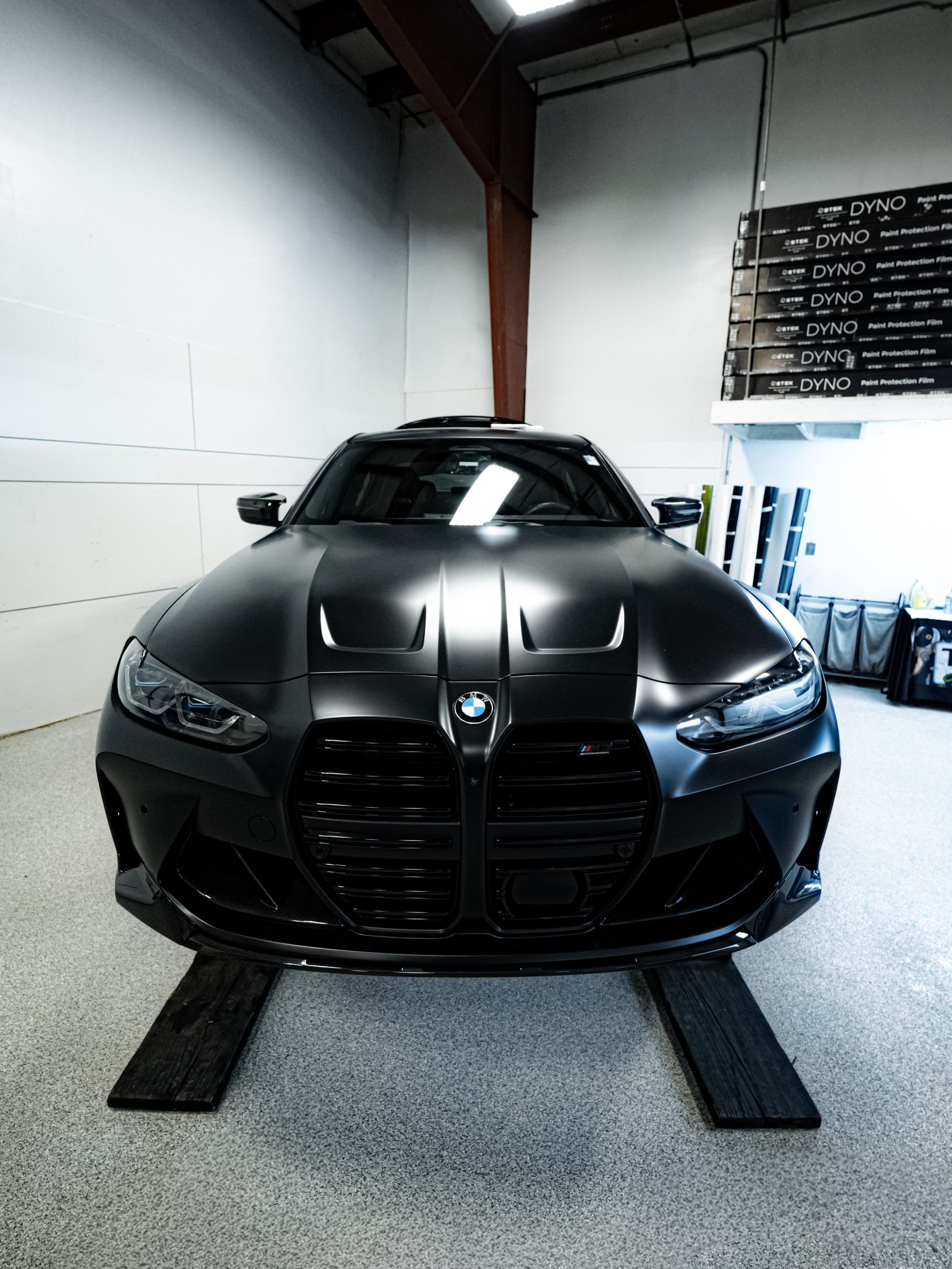 Matte black sports car parked indoors on ramps in a garage-like setting