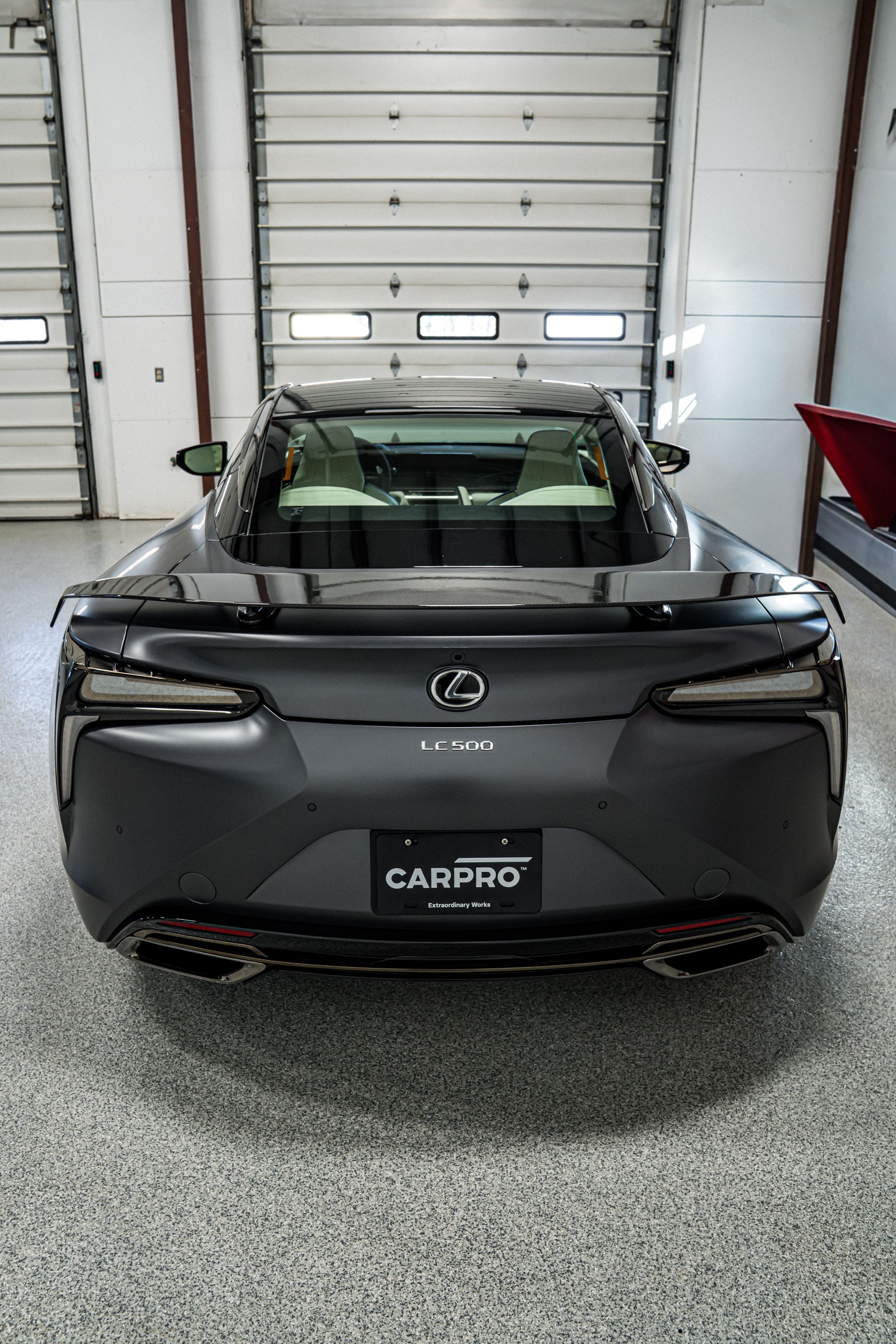 Rear view of a black Lexus car parked inside a garage.