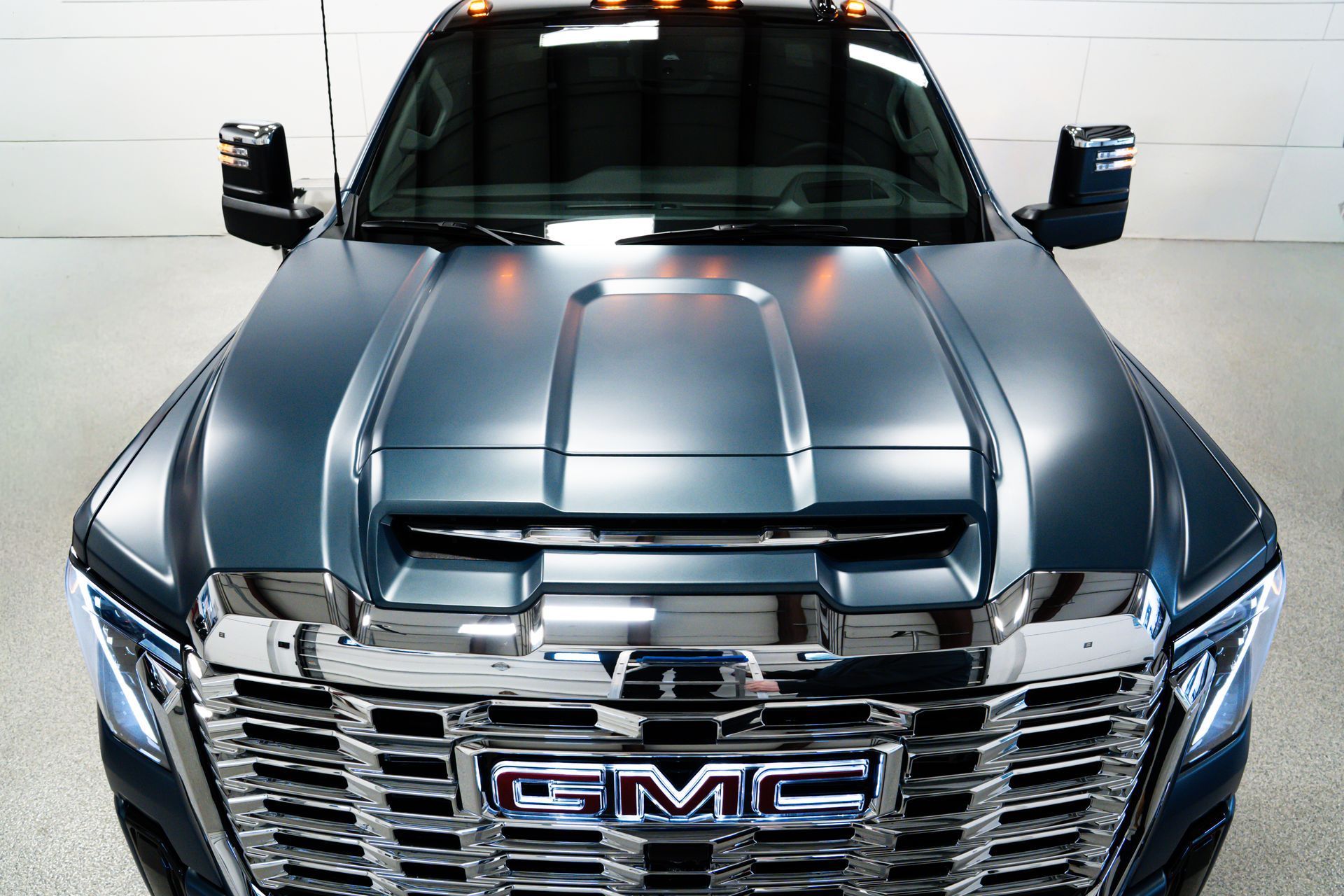Front view of a gray GMC truck with a chrome grille in a studio setting