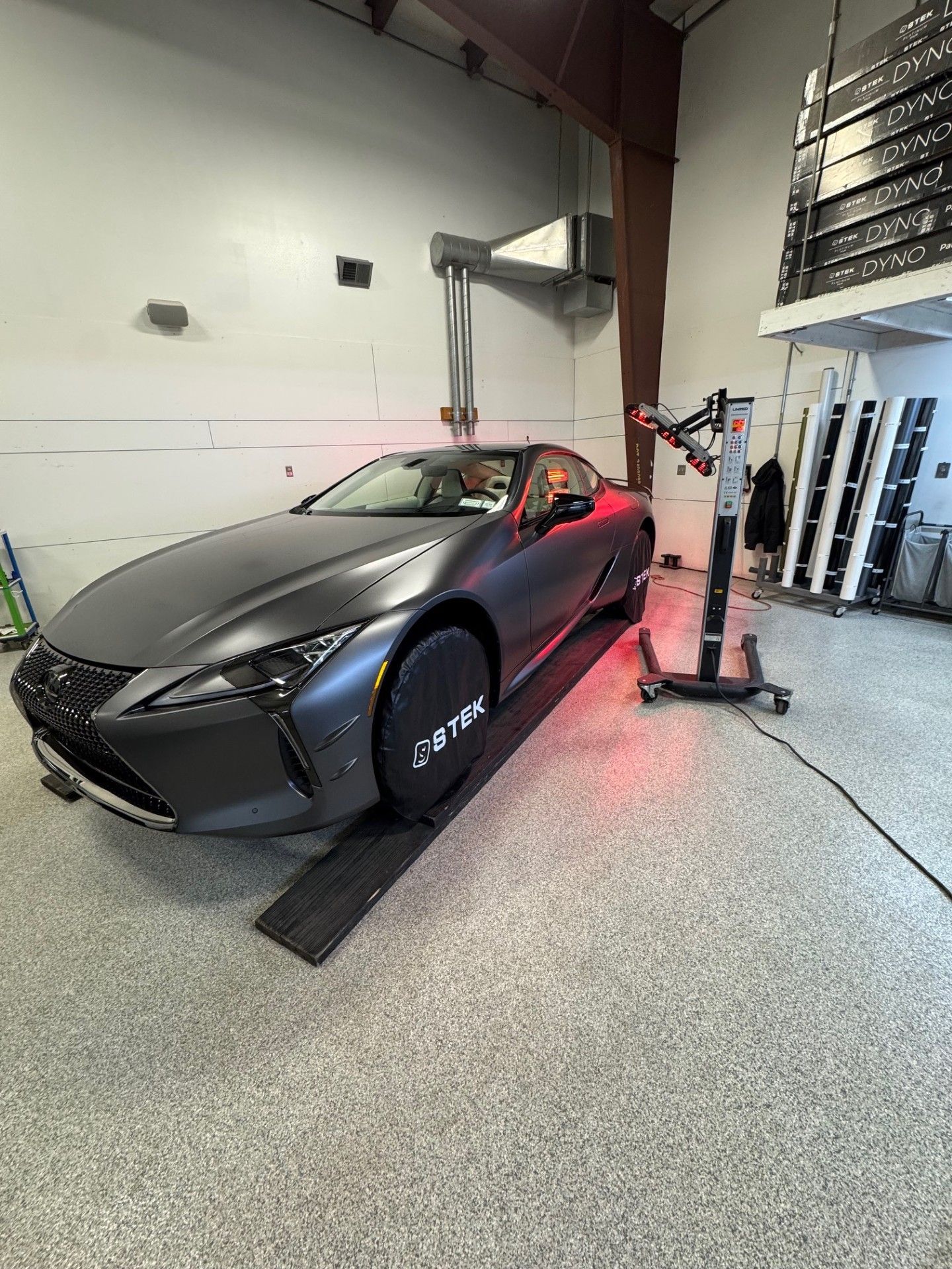Matte gray sports car parked indoors, front-left view, with black wheels and red brake calipers