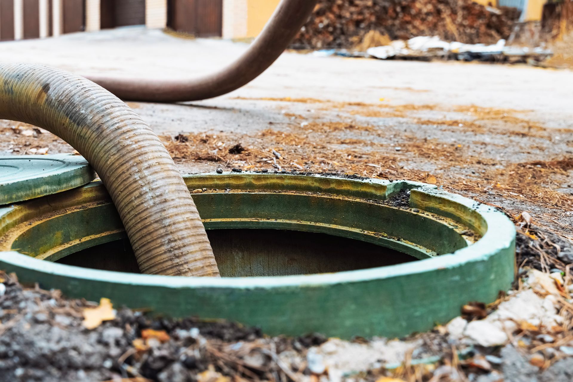 Septic pumping hose removing waste from a residential septic tank