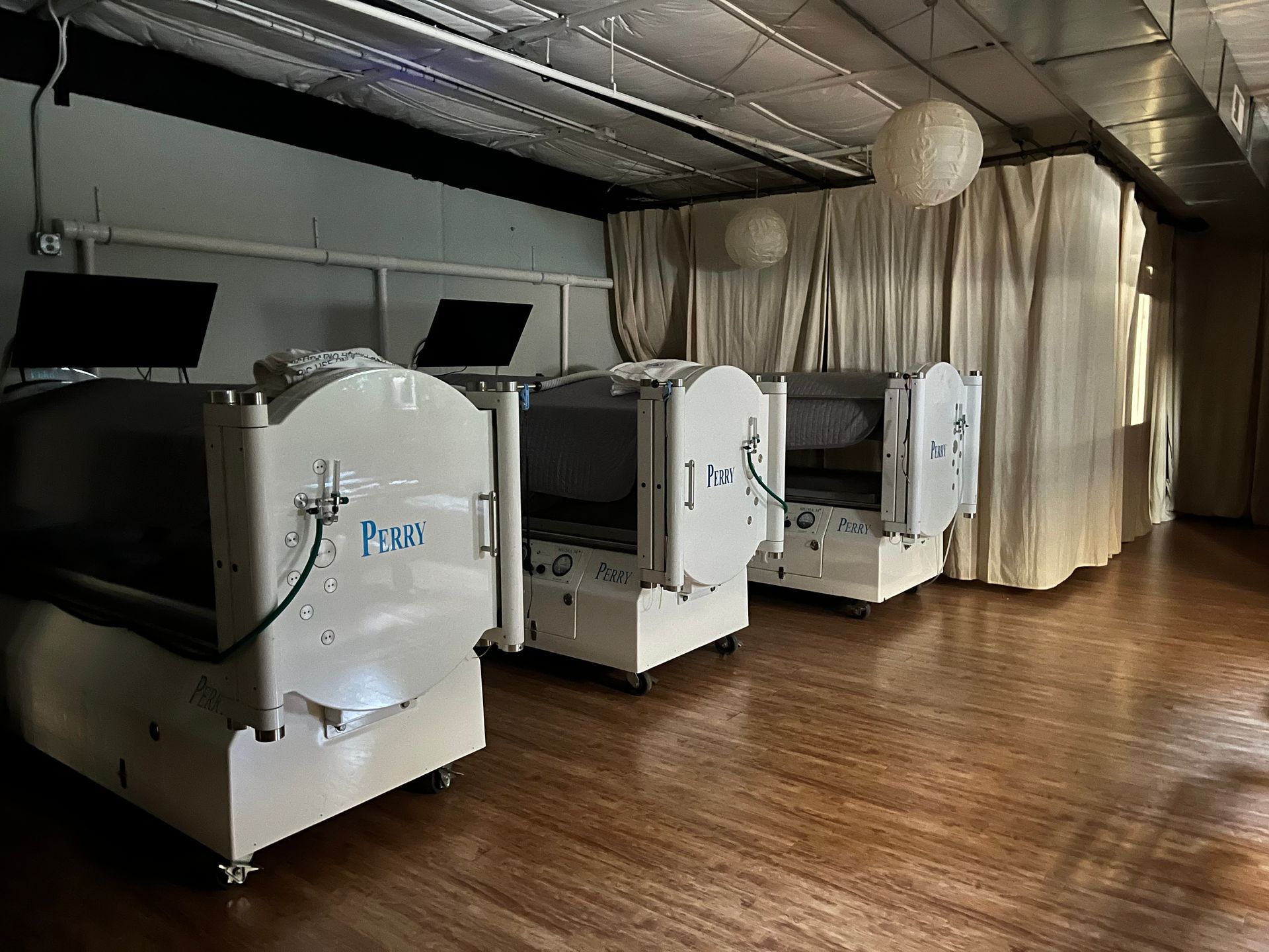 Indoor event space with white gaming pods lined on a wood floor under silver ceiling lights