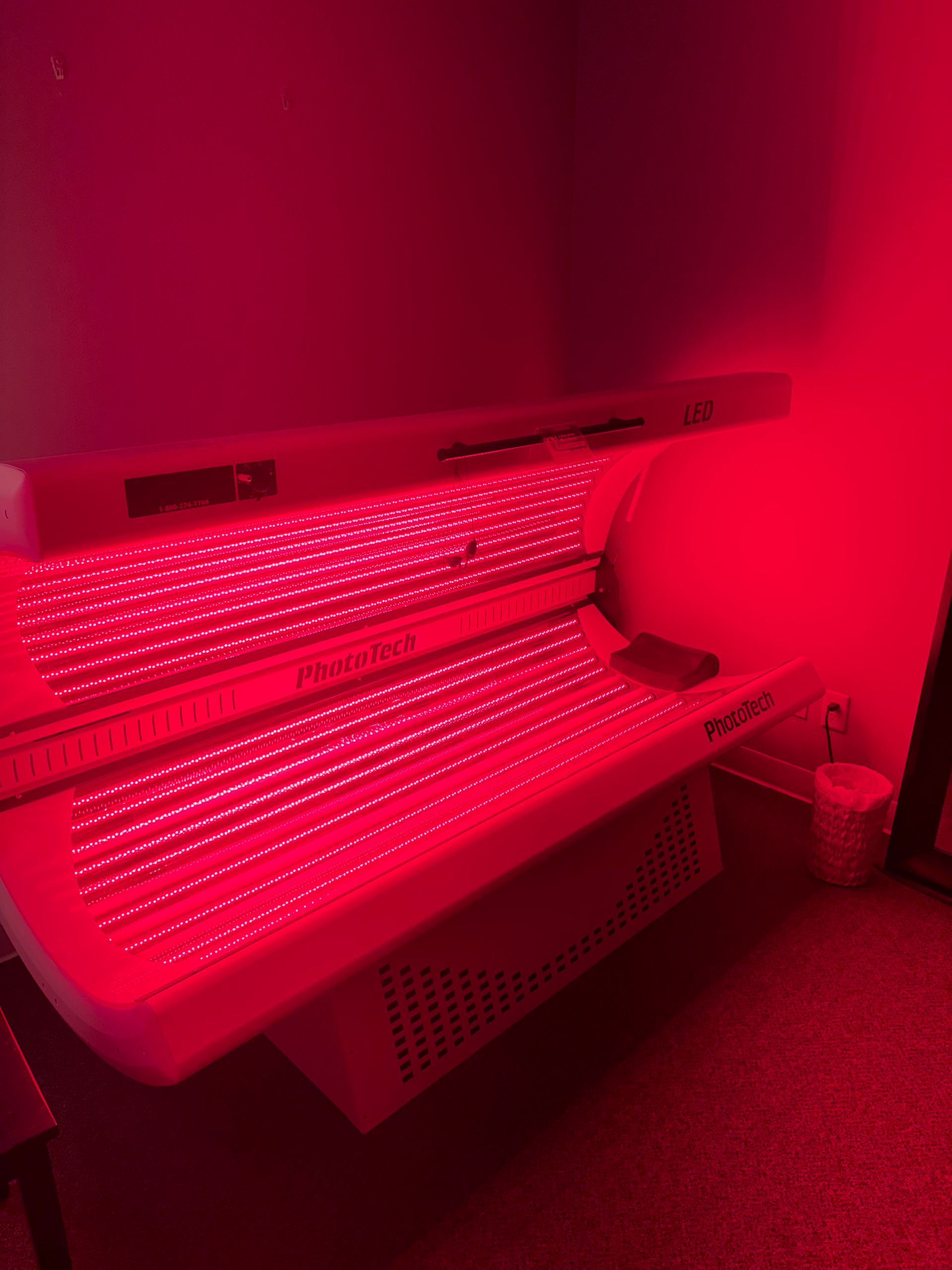 Red-lit tanning bed in a small room, glowing with rows of lights.
