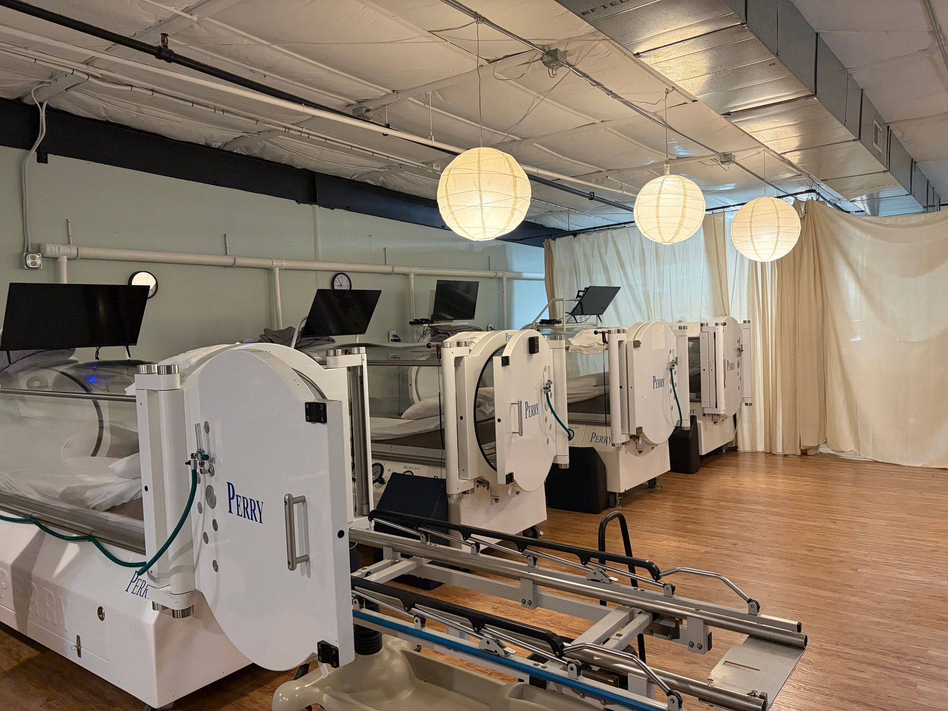 White dialysis machines in a clinical room with hanging paper lanterns and curtains