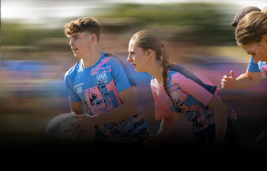 Two runners in blue and pink jerseys sprint side by side in a blurred outdoor race.