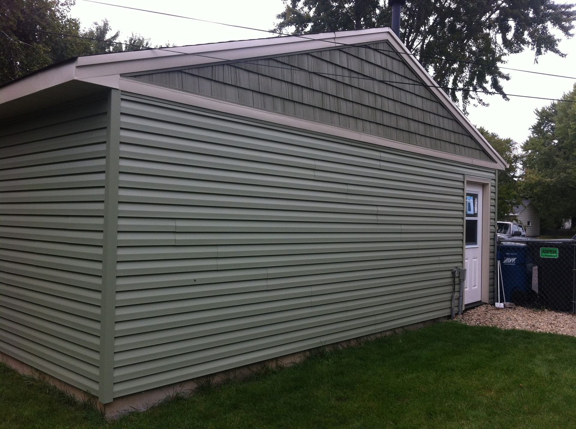 A garage with a green siding and a white door