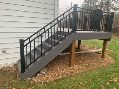 A deck with stairs leading up to it and a black railing.