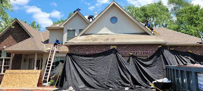 A large brick house is being remodeled with a roof being installed.