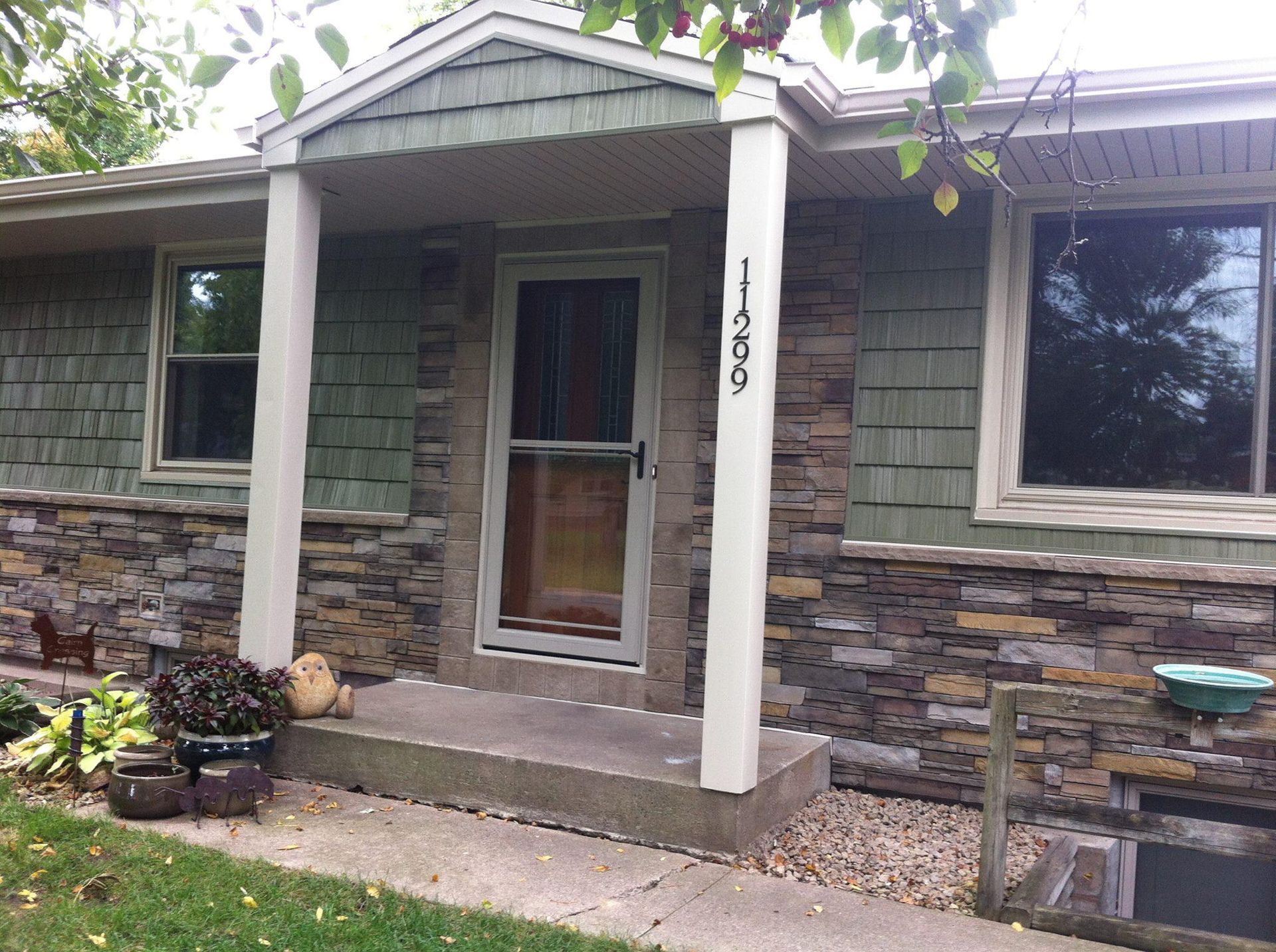 A house with a stone facade and a porch with the number 1465 on it
