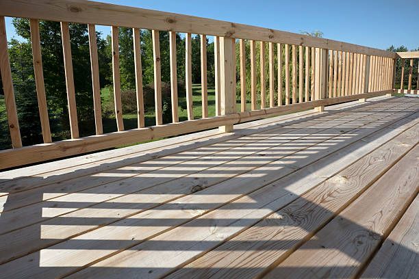 A wooden deck with a wooden railing and trees in the background