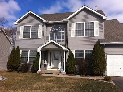 A large house with a gray siding and white shutters