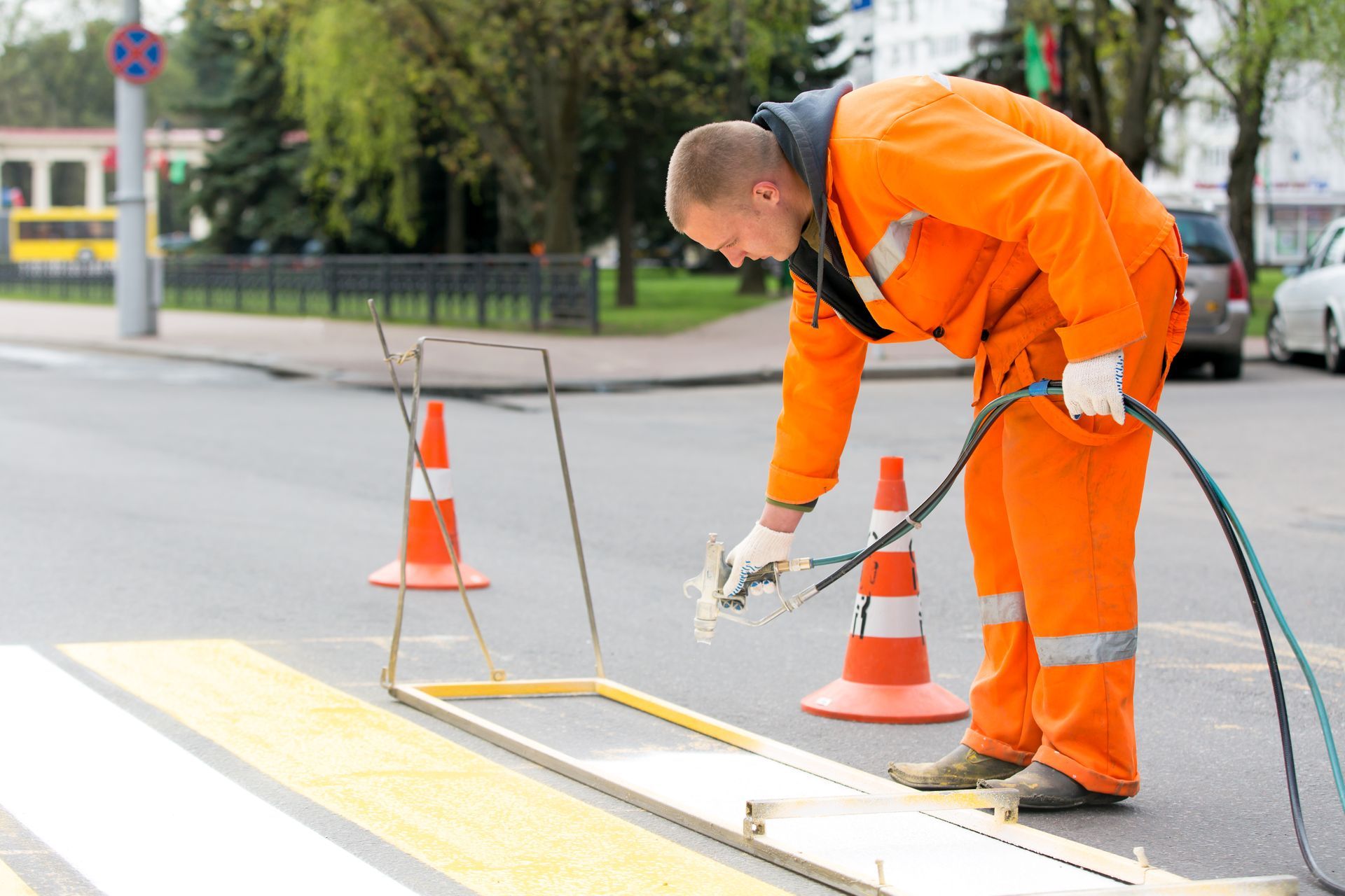Road painter marking street lines using a paint sprayer gun