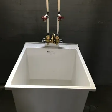 Large white utility sink with brass faucets against a dark wall