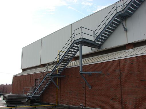 Brick building with exterior metal stairs and a white rooftop enclosure
