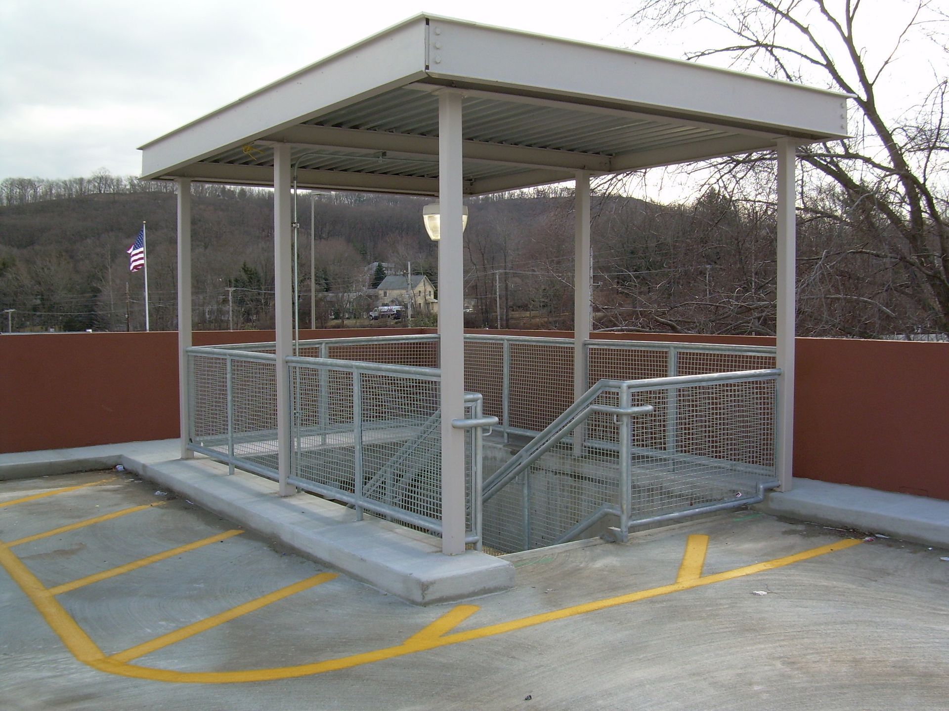 Covered outdoor accessibility ramp with metal railings and a roof on a parking deck