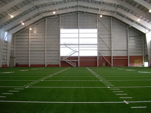 Indoor football field inside a large white dome with green turf and yard lines