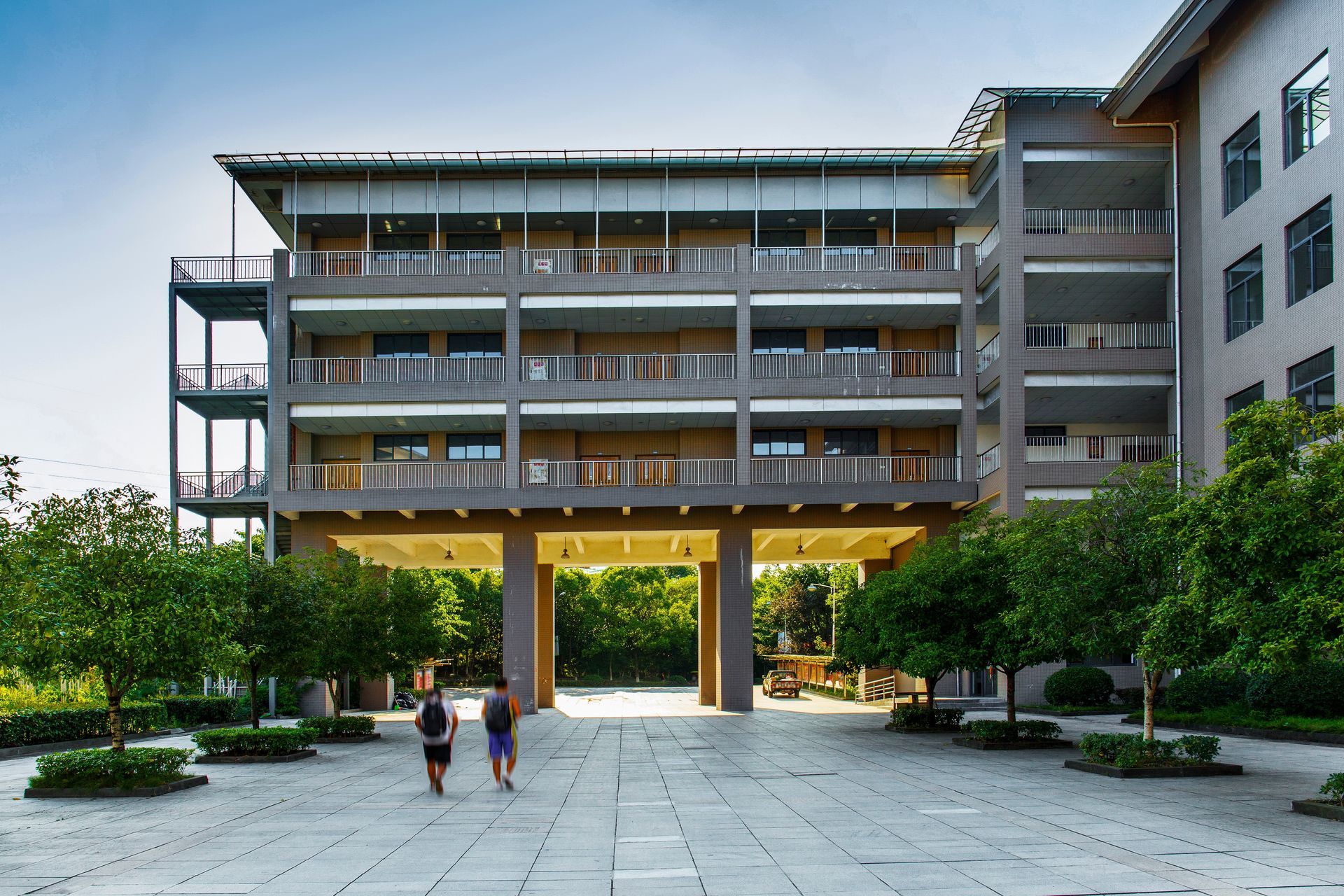 Two people are walking in front of a large building