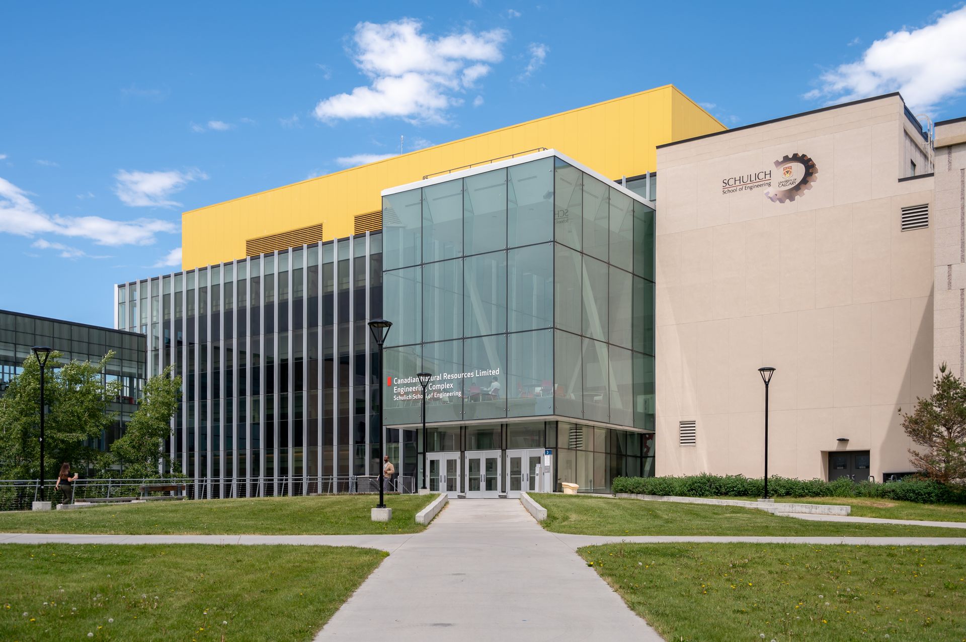 A large building with a yellow roof is surrounded by grass and trees.