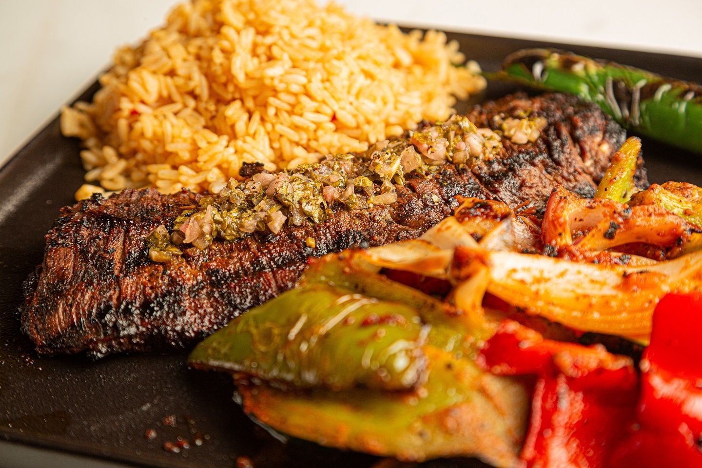A close up of a plate of food with meat , rice and vegetables.