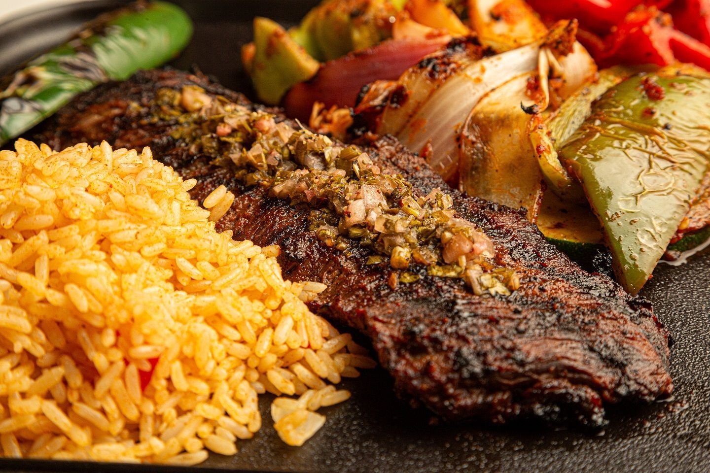 A close up of a plate of food with rice and meat on a table.