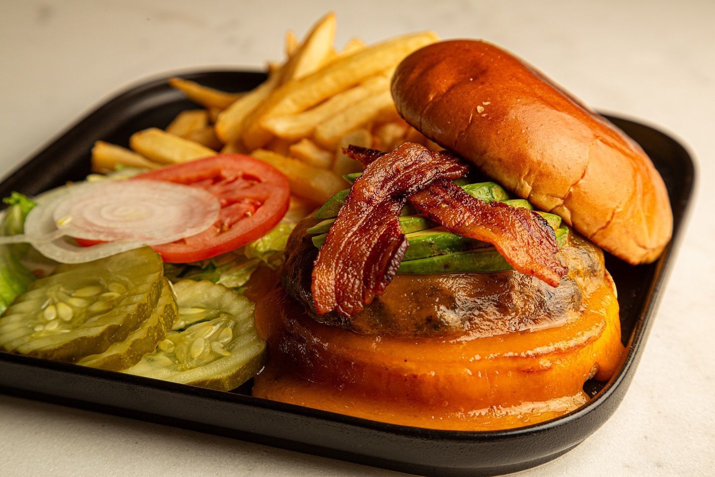 A close up of a hamburger and french fries on a plate.
