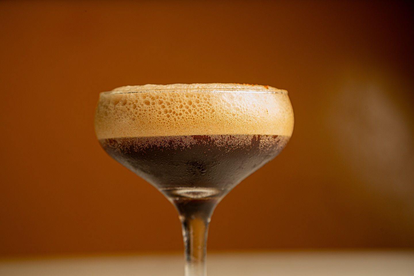 A close up of a martini glass filled with coffee on a table.