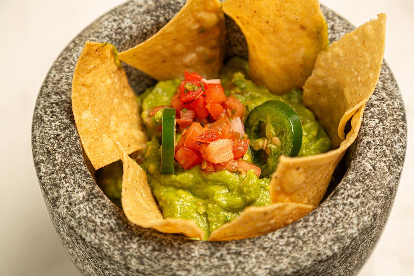 A bowl of guacamole and tortilla chips in a mortar and pestle.