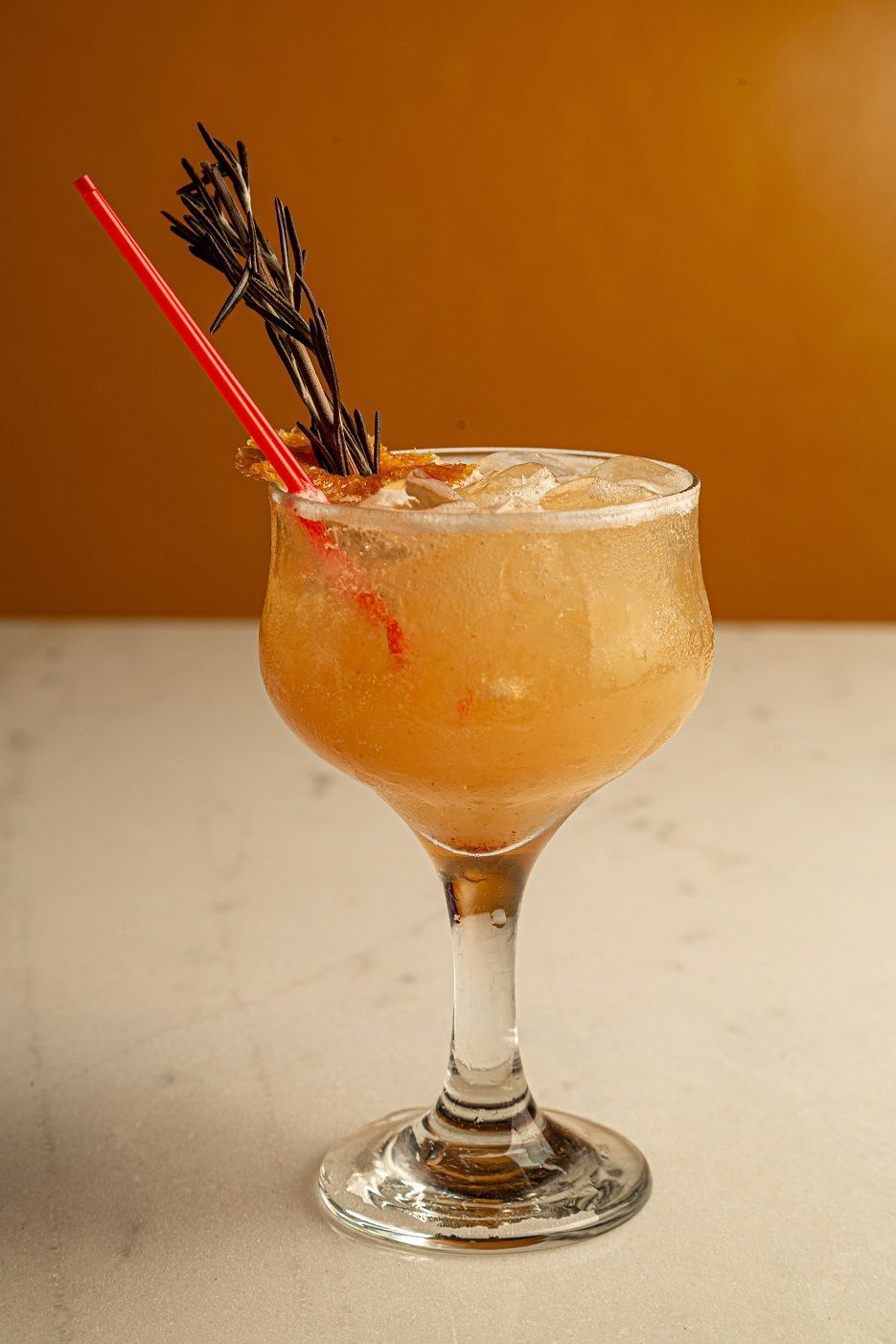 A close up of a drink in a glass with a straw on a table.