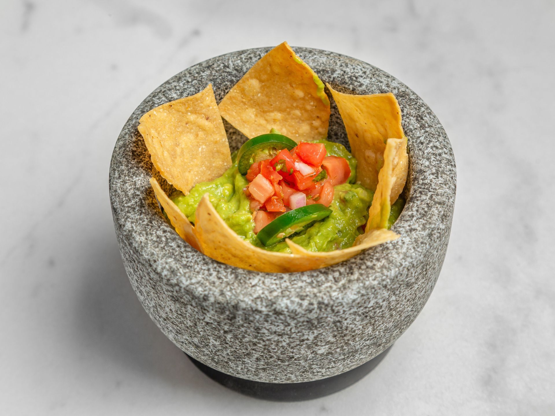 A bowl of guacamole and tortilla chips in a mortar and pestle.