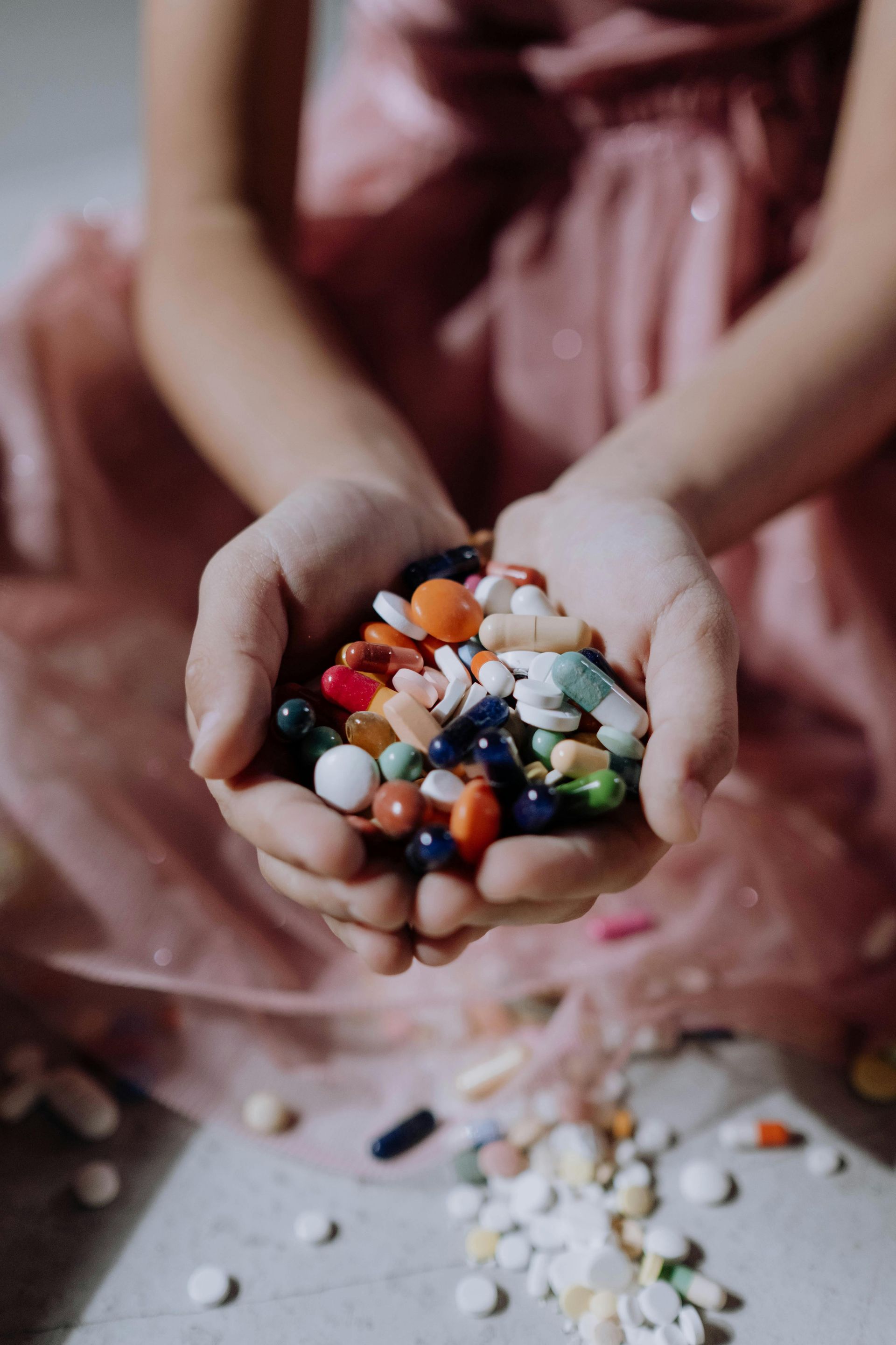 A woman is holding a pile of pills in her hands.