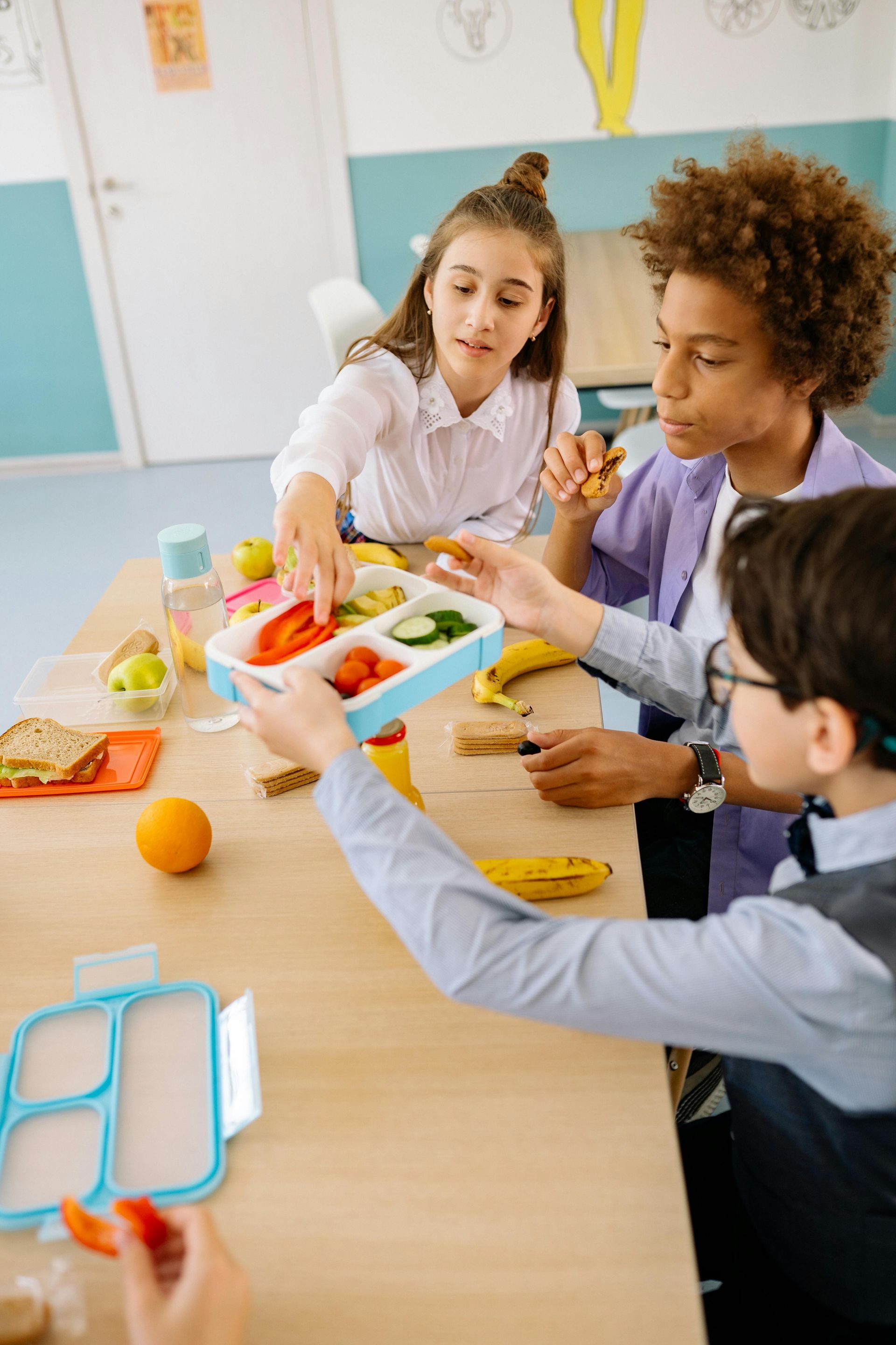 A group of children are sitting at a table eating lunch.