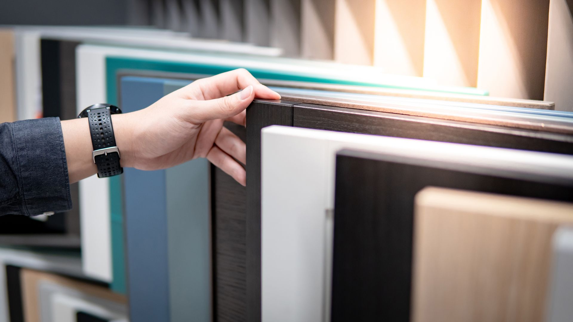 Hand browsing color and wood finish sample panels on a display rack