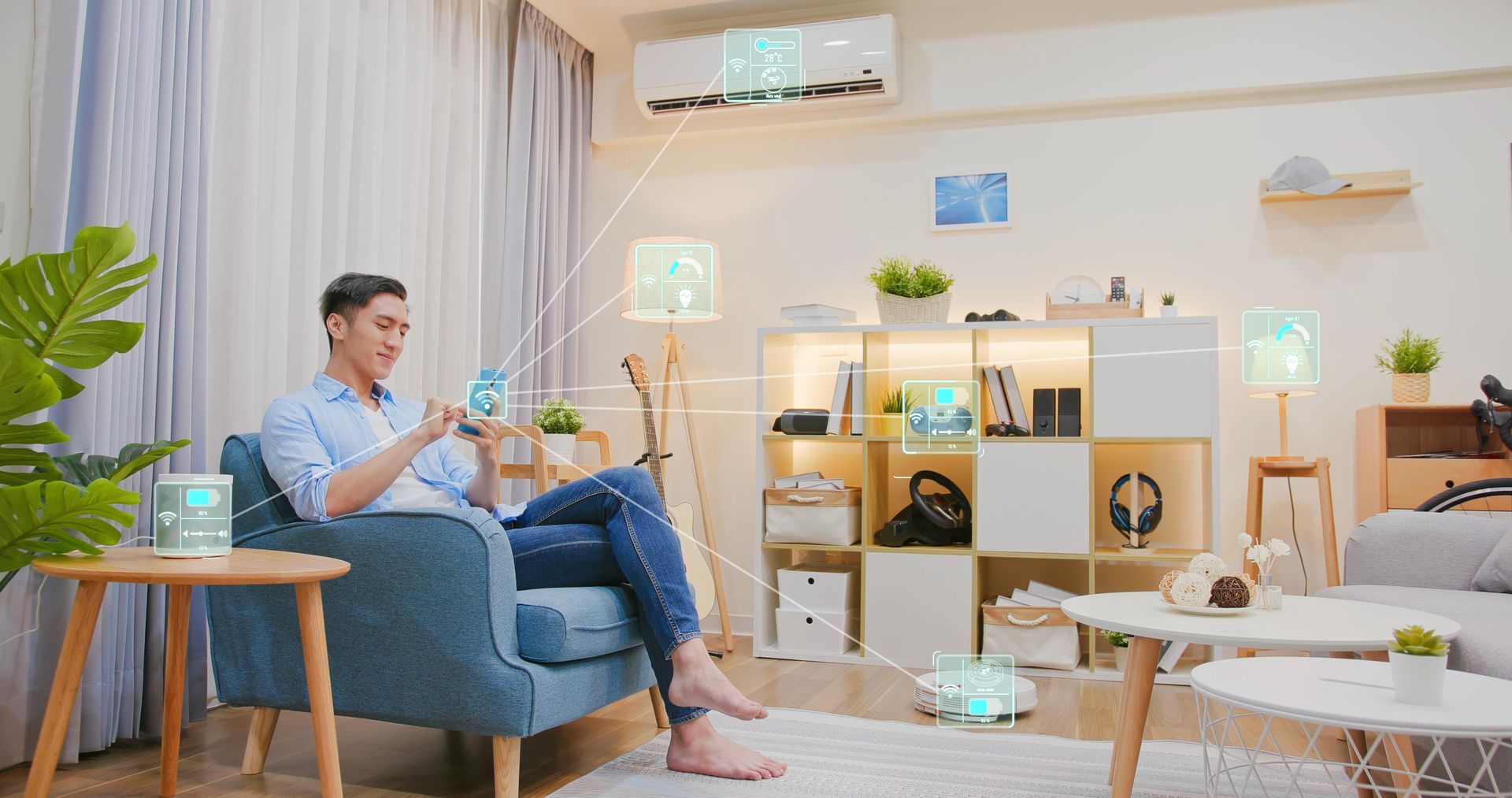 Man sitting on a blue armchair in a bright living room, using a smartphone with a relaxed posture