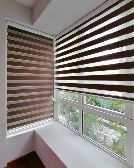 Dormitorio luminoso y minimalista con una cama beige, persianas a rayas y luz solar cálida en el suelo.