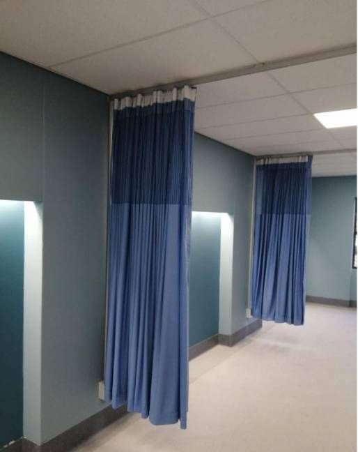 Pasillo del hospital con cortinas azules que dan privacidad y que cuelgan a lo largo de las paredes.
