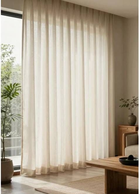 Cortinas blancas translúcidas junto a una ventana soleada en una sala de estar minimalista.