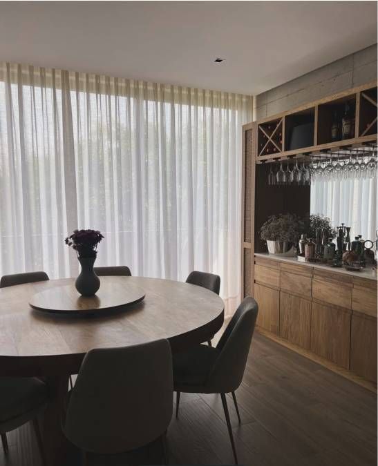 Cortinas blancas translúcidas junto a una ventana soleada en una sala de estar minimalista.