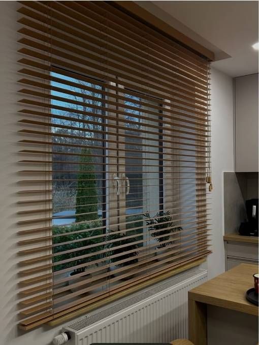 Persianas de madera que cubren puertas de cristal en una habitación de color claro.